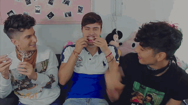 three young men are sitting on a couch and one of them is wearing a shirt that says ' abercrombie ' on it
