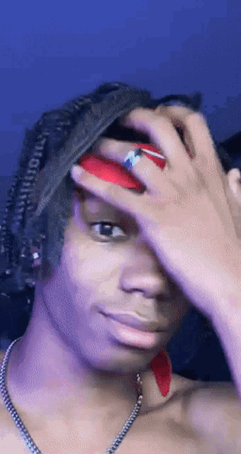 a young man with dreadlocks is covering his face with his hands