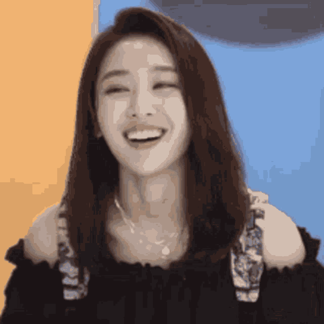 a woman in a black off the shoulder top is smiling and laughing .