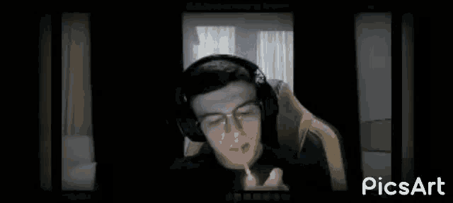 a man wearing glasses and headphones is smoking a cigarette while sitting in a chair .