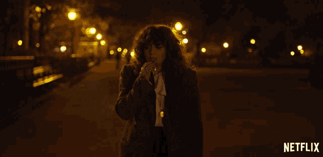 a woman is walking down a street at night with a netflix logo in the corner