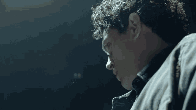 a man with curly hair looks down at something