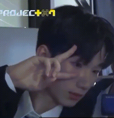 a man in a suit and tie is making a peace sign with his hands in front of his face .