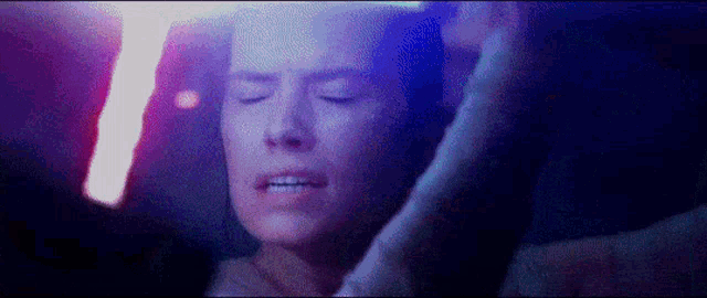 a close up of a woman 's face with her eyes closed and a light shining on her face .