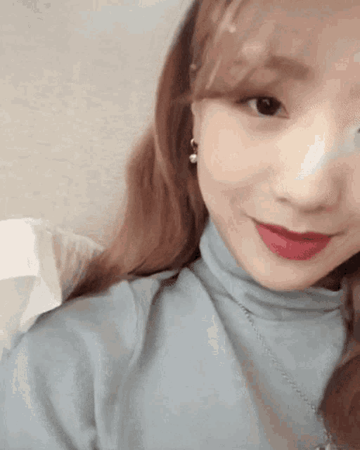 a close up of a woman 's face wearing a blue turtleneck and red lipstick