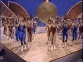 a group of people are running on a track in front of a large globe .