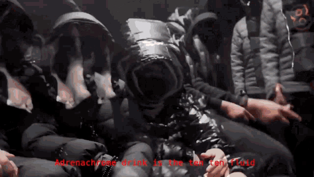 a group of people sitting in a dark room with the words " adrenaline drink is the ten ton fluid " on the bottom right