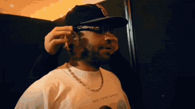 a man wearing a hat and sunglasses is wearing a shirt that says feliz / happy