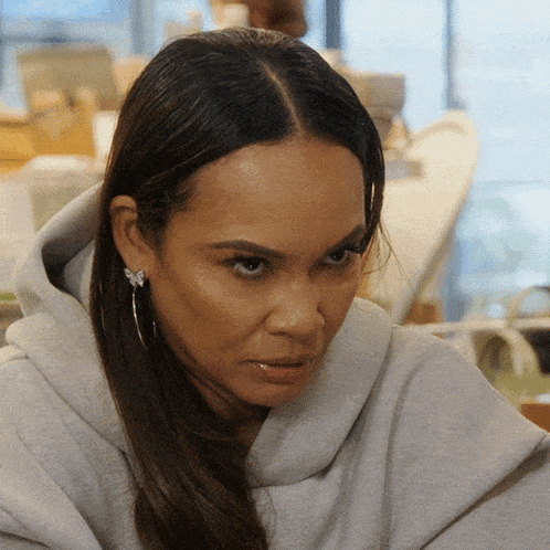 a close up of a woman wearing a grey sweatshirt and earrings