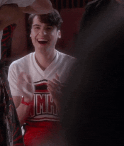 a man wearing a cheerleader shirt that says mrs is smiling