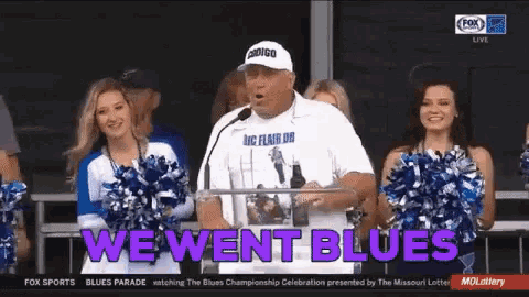 a man is giving a speech in front of cheerleaders and says " we went blues "