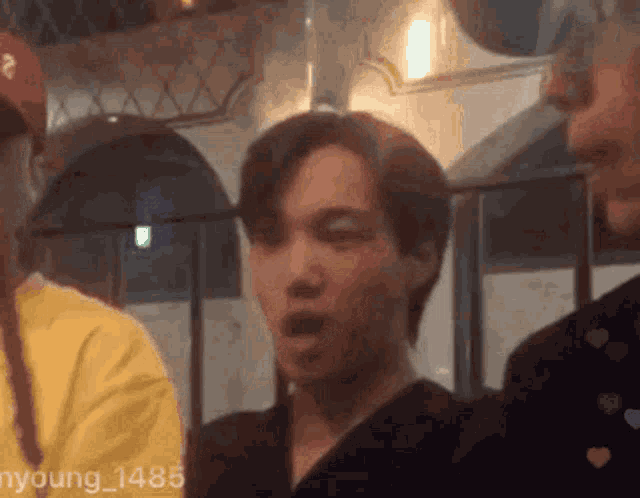 a man with a surprised look on his face is standing next to another man in a yellow shirt .