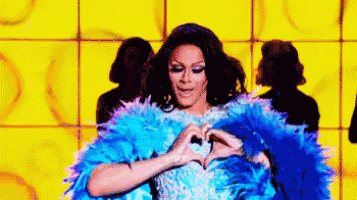a woman in a blue fur coat is making a heart shape with her hands