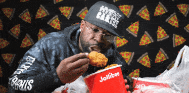 a man wearing a hat that says hyphy cartel is eating chicken