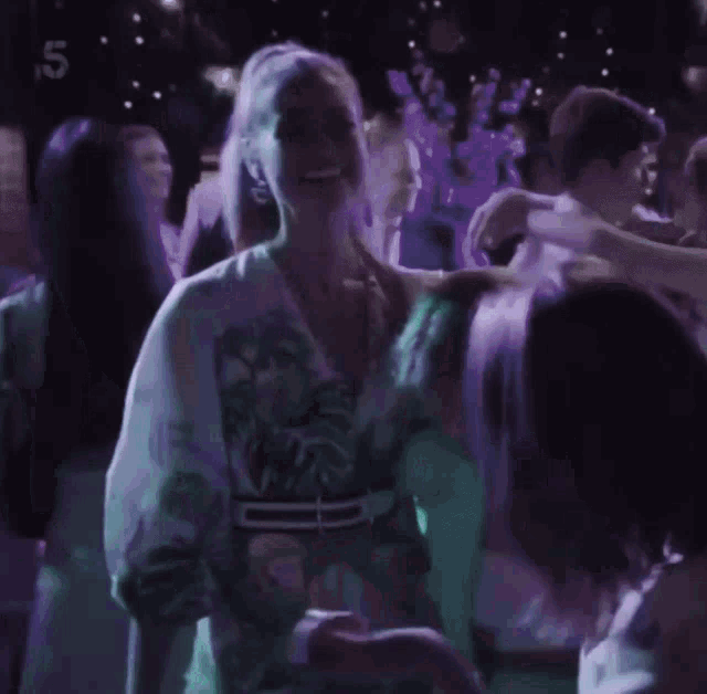 a group of people are dancing in a dark room with the number 5 on the bottom left