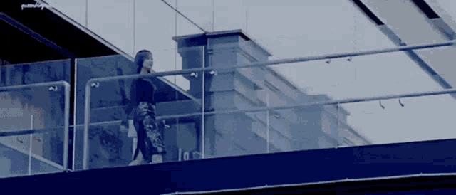a woman is standing on a balcony overlooking a building
