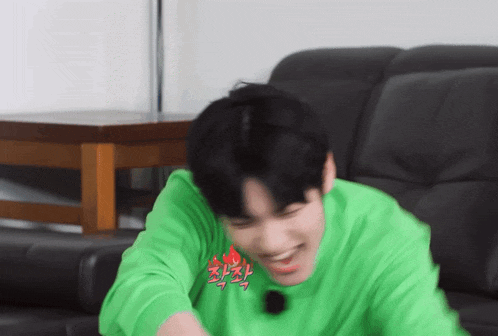 a young man wearing a green shirt with the word fire on it is laughing