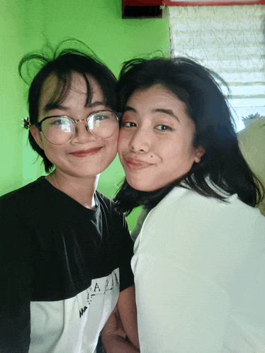 two girls are posing for a picture with one wearing a shirt that says ' aa ' on it