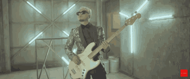 a man in a suit is playing a bass guitar in a room