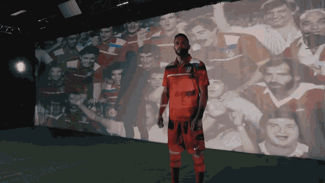 a man standing in front of a wall with a picture of a soccer team behind him