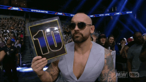 a man wearing sunglasses holds up a sign that says 10