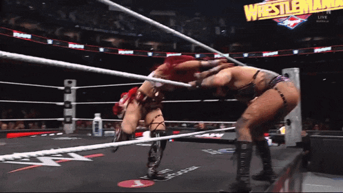 two women are wrestling in a ring with the words wrestlemania behind them