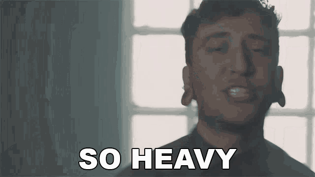a man is singing a song and the words so heavy are above him