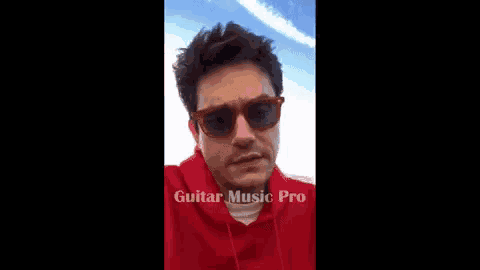 a man wearing sunglasses and a red hoodie .