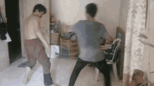 two men without shirts are dancing in a room with boxes in the background