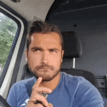 a man in a blue shirt is sitting in a car