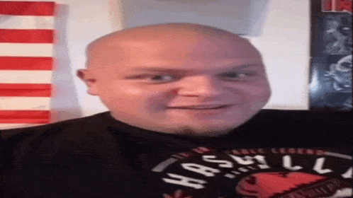 a bald man with a beard is wearing a black shirt with the word hash on it .