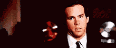a man in a suit and tie is smoking a cigarette and looking at the camera .
