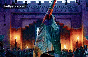 a man is standing in front of a castle holding a sword in his hand .