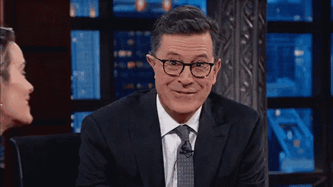 a man wearing glasses and a suit is smiling while talking to a woman