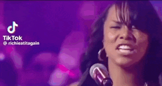 a woman is singing into a microphone with her eyes closed .