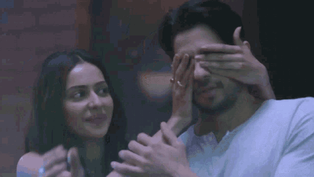 a woman covering a man 's eyes with her hand