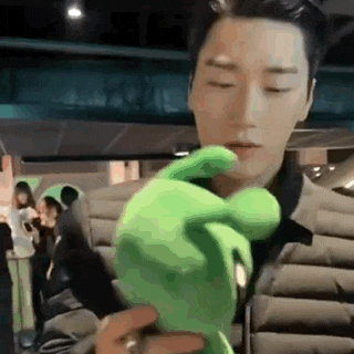 a man is holding a green stuffed animal in his hand in a car .