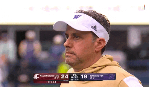 a man wearing an adidas headband watches a football game