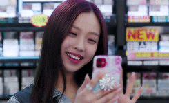 a woman is taking a picture of herself with her phone in front of a new sign