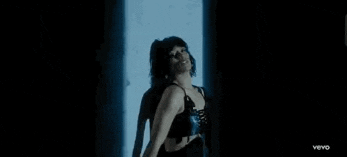 a woman in a black bra is dancing in front of a blue light .
