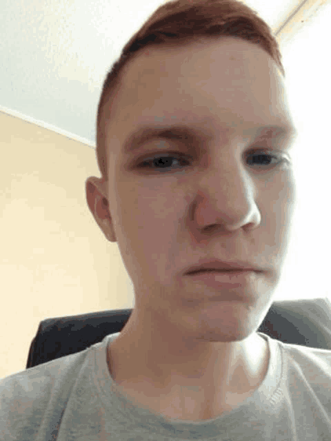 a young man with red hair and a gray shirt is making a funny face .