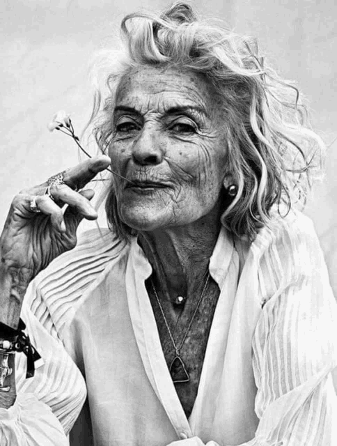 a black and white photo of a woman holding a flower