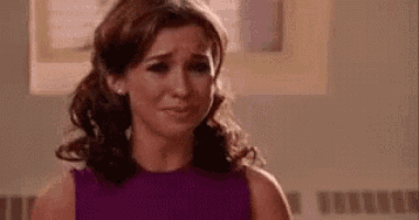 a woman in a purple dress is crying and looking at the camera .
