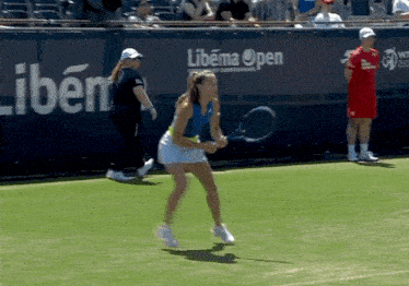 a woman is holding a tennis racquet on a court in front of a sign that says libema open