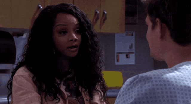 a man in a hospital gown talks to a woman