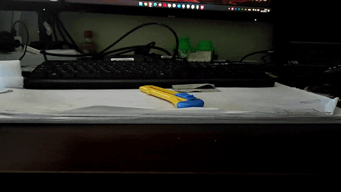 a yellow and blue knife is sitting on a desk next to a keyboard