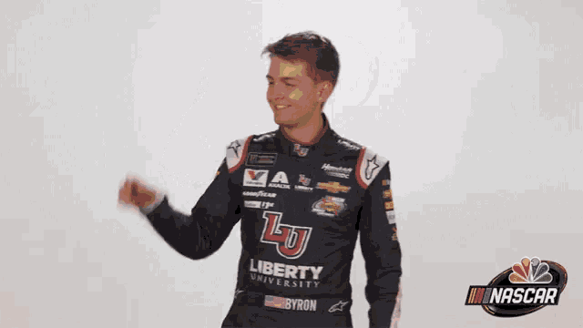 a man in a liberty university racing uniform holds his fist up