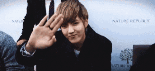 a man waving his hand in front of a nature republic sign