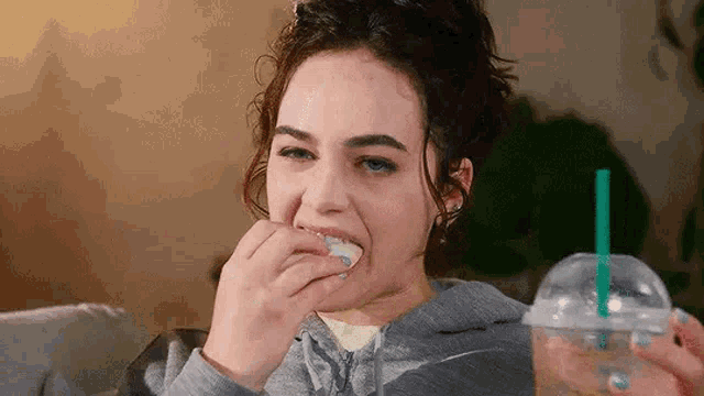 a woman is eating a piece of food and drinking a drink .