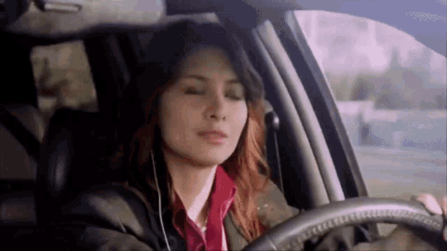 a woman wearing headphones is driving a car .
